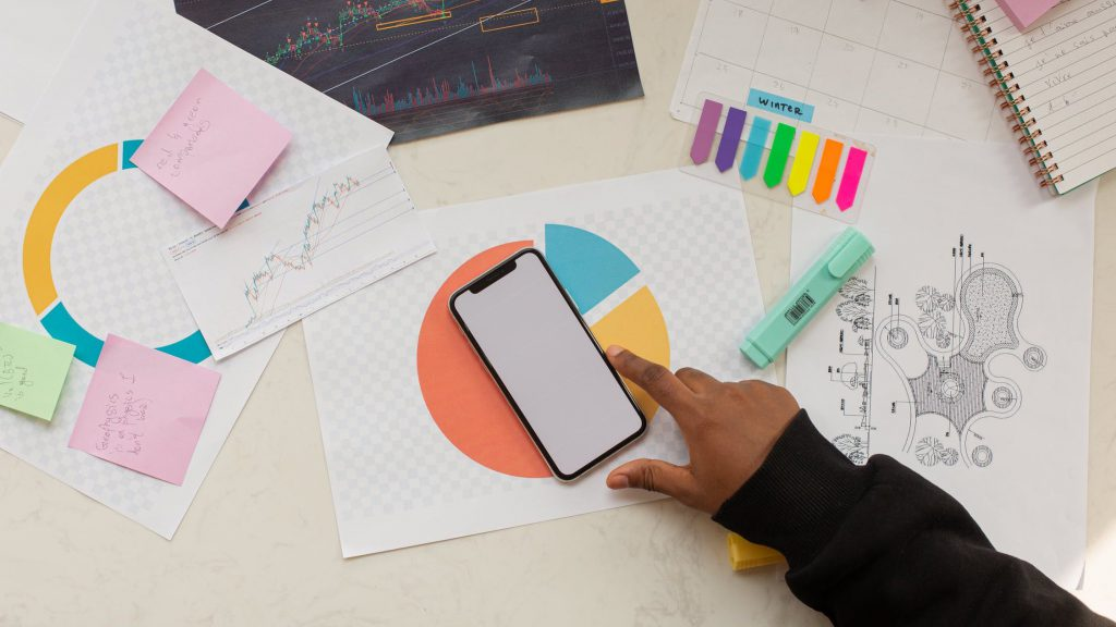 n individual focused on their smartphone, surrounded by a cluttered table adorned with papers and pens.